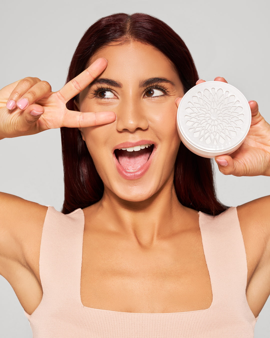 Lächelnde Frau mit Victory-Zeichen hält eine Dose Zahnaufhellungspulver von OnlySmile neben ihrem Gesicht