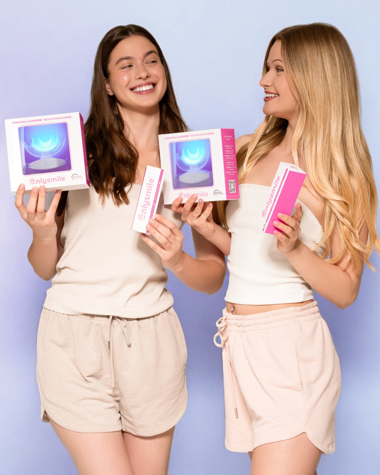 Zwei junge Frauen halten jeweils ein Zahnaufhellungsset und ein Whitening-Gel von OnlySmile – fröhliche Produktpräsentation