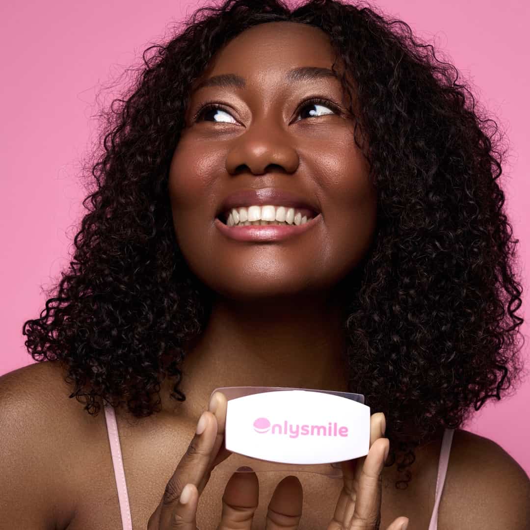 Glücklich lächelnde Frau mit strahlend weißen Zähnen hält ein OnlySmile-Zahnaufhellungsgerät