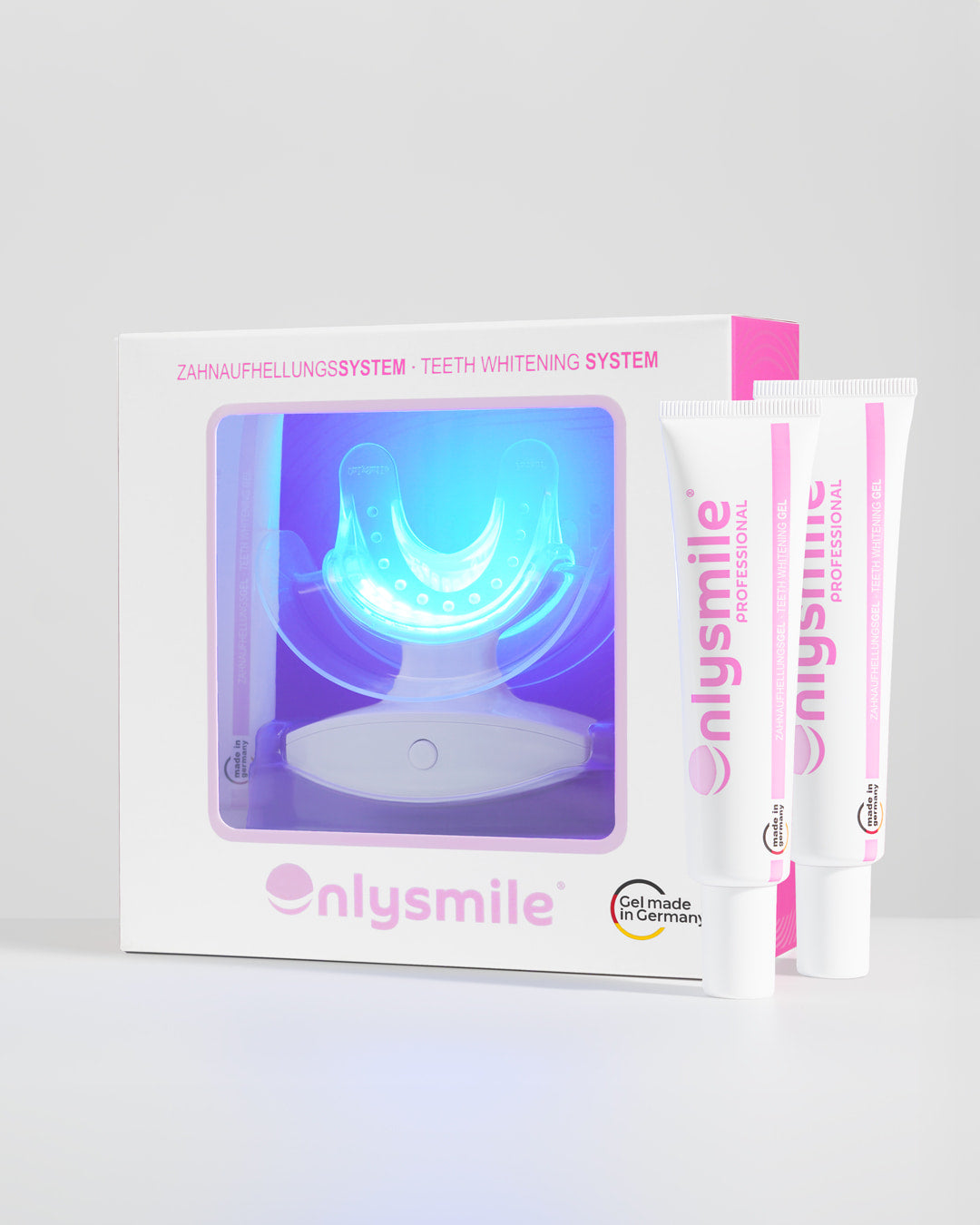 OnlySmile Zahnaufhellungsset und zwei Zahnaufhellungsgelen in weiß-pinker Verpackung vor hellem Hintergrund.